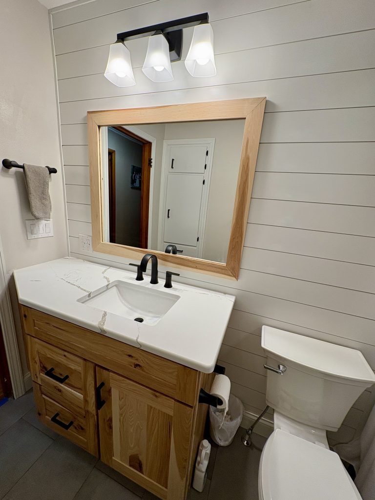 Custom maple bathroom vanity with quartz countertop and matte black faucet in a bright hallway bathroom remodel by Kleeberger Contracting Services in Northwest Ohio.