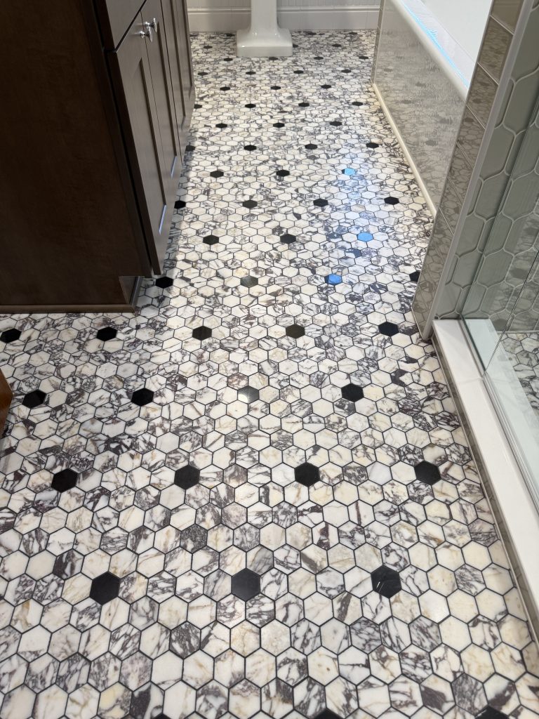 marble hexagon tile floor with black accent pattern in bathroom remodel